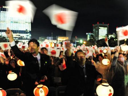 Una multitud de japoneses enarbolan la bandera de su país para celebrar el 20 aniversario de la coronación de Akihito
